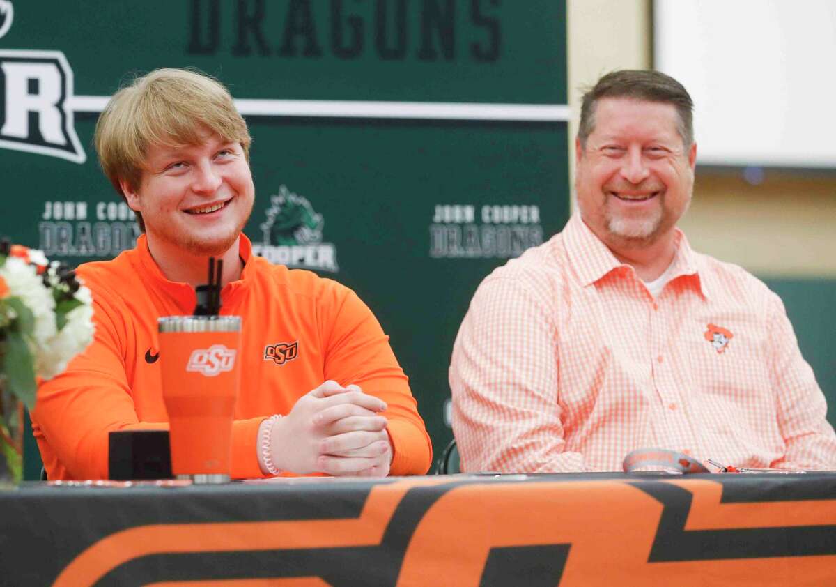 Owen Woodside, left, rolls his eyes at a joke by Athletic Director John Hoye before signing to play football for Oklahoma State University during a signing ceremony at The John Cooper School, Thursday, April 7, 2022, in The Woodlands.