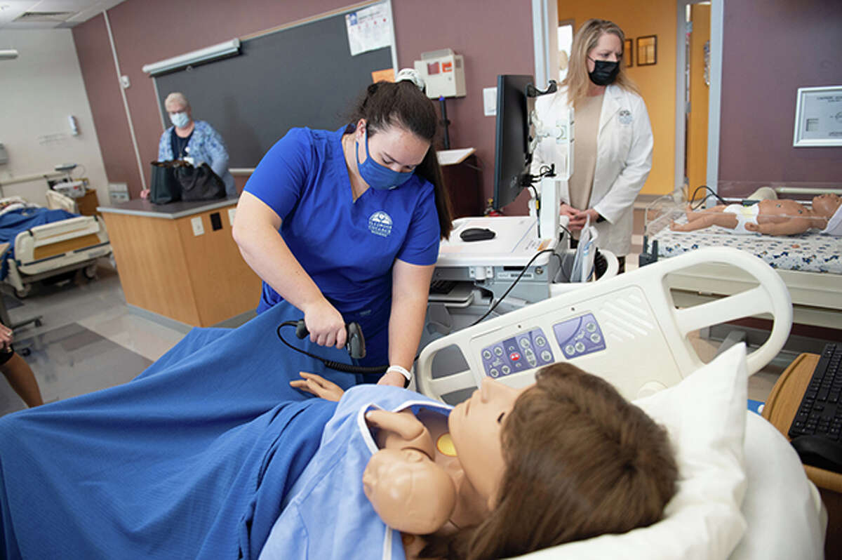 Instructor Karen Baur (from left) looks on as Illinois College nursing students Maddie McKeown and Heidi Sipes practice on nursing simulation lab equipment.