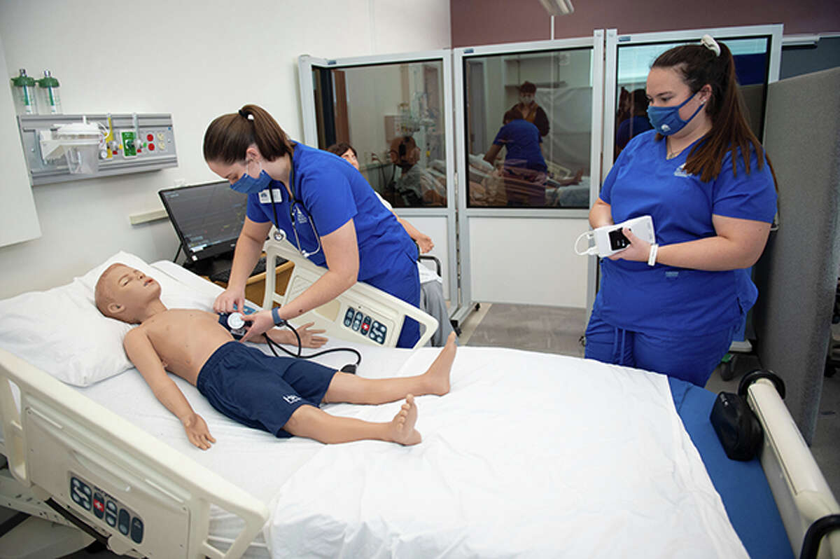 Illinois College nursing student Lucy Wubker (left) practices on a simulator of a 5-year-old child as fellow student Maddie McKeown watches.