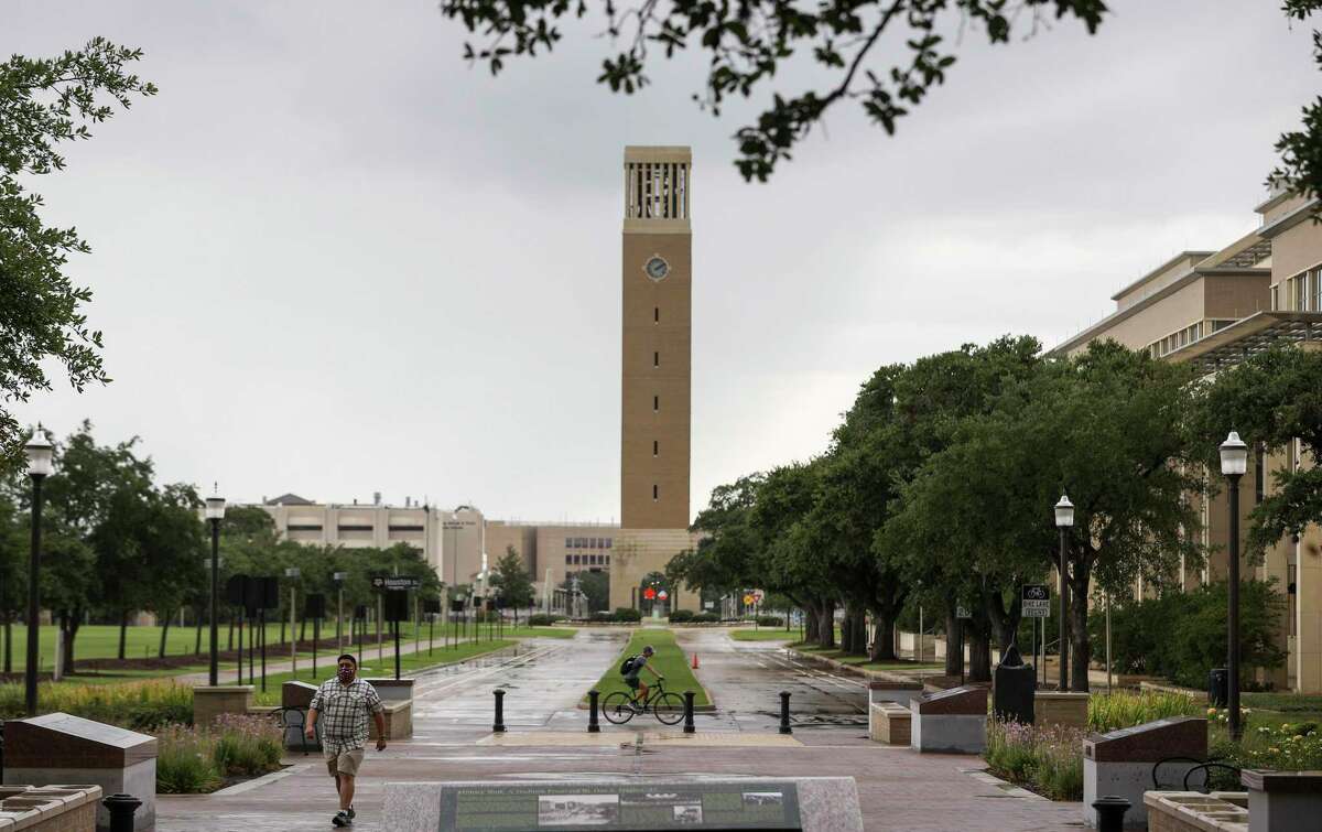 People pass through campus as the Albritton Bell Tower is seen in the background on Tuesday, July 7, 2020, at Texas A&M University in College Station.