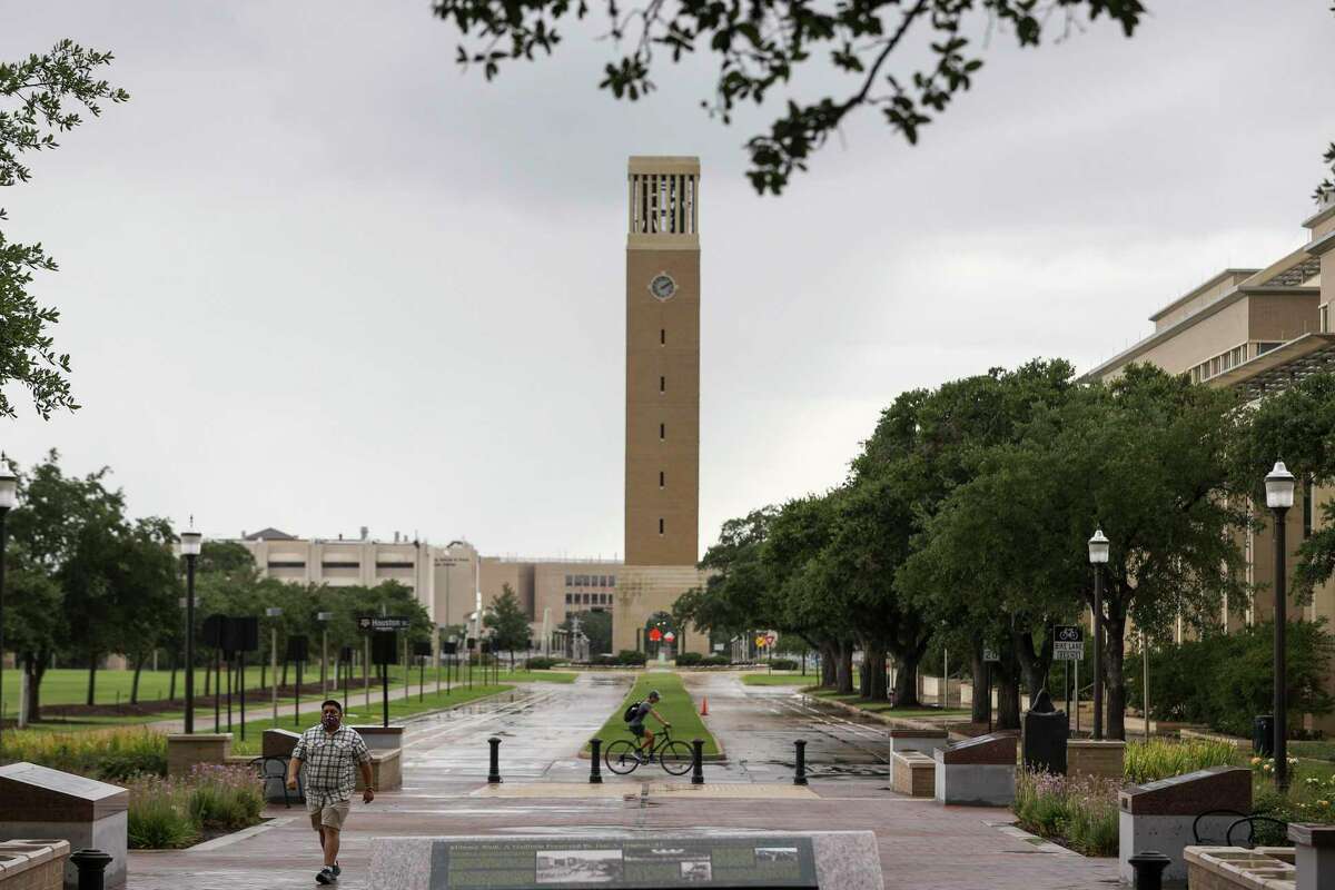 People pass through campus as the Albritton Bell Tower is seen in the background on Tuesday, July 7, 2020, at Texas A&M University in College Station.