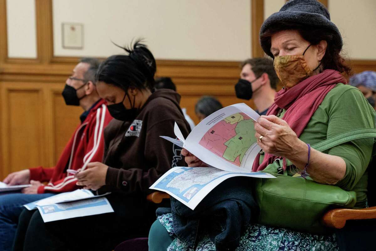 Protesters sit in an overflow room at San Francisco City Hall on Wednesday to voice their concerns about the redistricting of their communities.