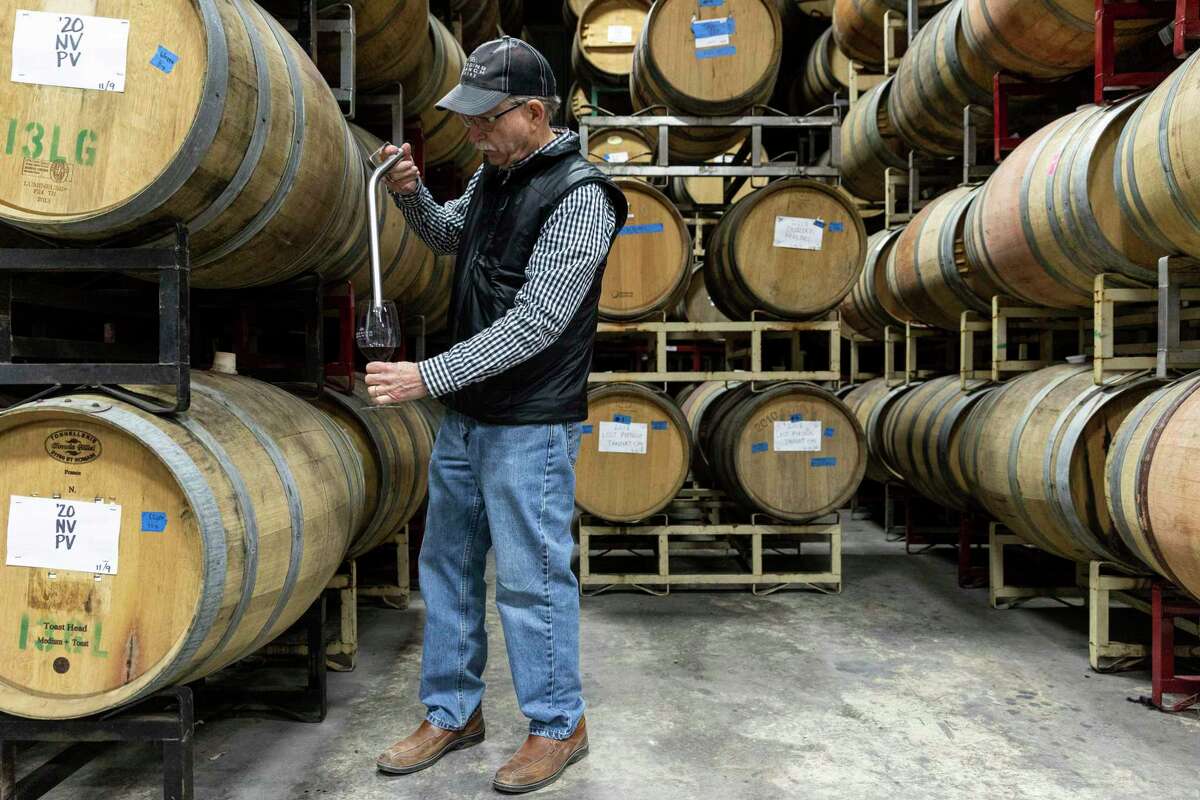Bob Young, owner of Bending Branch Winery, pulls a sample from a barrel using a wine thief inside the cellar at Bending Branch Winery.