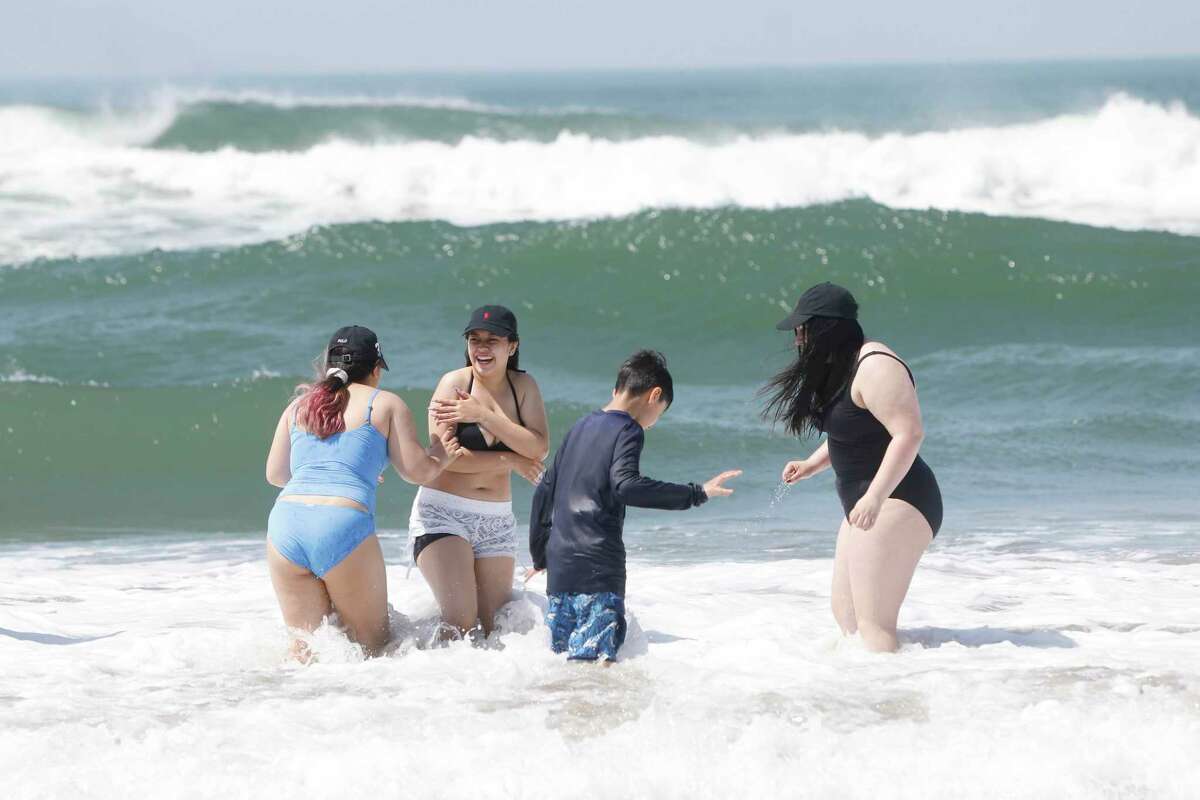 (l to r) Scarlett Rojas, 12; Tatian Padilla, 15, Michael Padilla, 10 and Ashley Rojas, 19, all of Oakland, play in waves on Ocean Beach as they enjoy the sun on their spring break on April 7, 2022 in San Francsico.