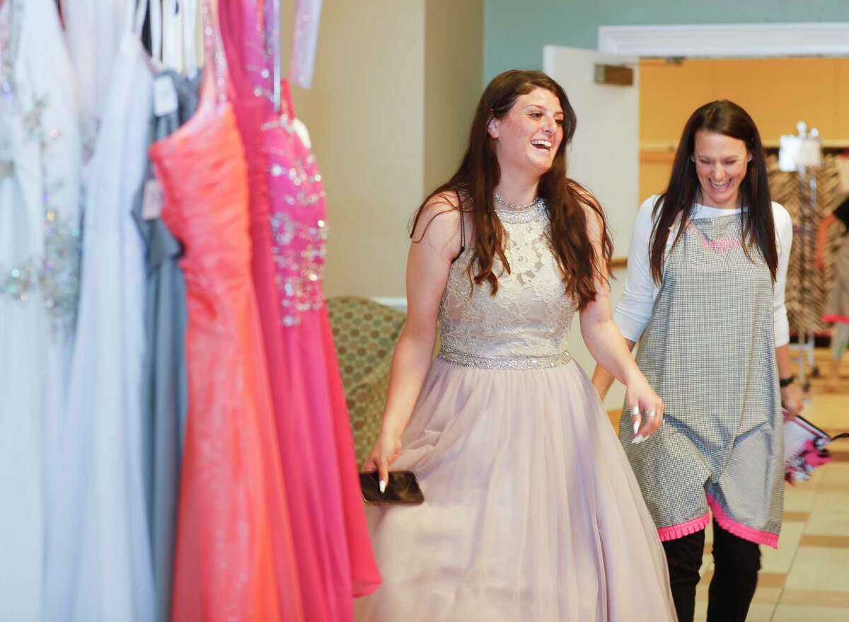Kaylee Riley, left, laughs with Angela Rosenkranz as she heads over to look for jewelry to match her new dress during Priceless Gowns at First Baptist Church Conroe, Thursday, April 7, 2022, in Conroe. The annual ministry, which returned to full capacity after being canceled in 2020 and scaled back in 2021, allows high school and junior teens to shop for their prom gowns for free.