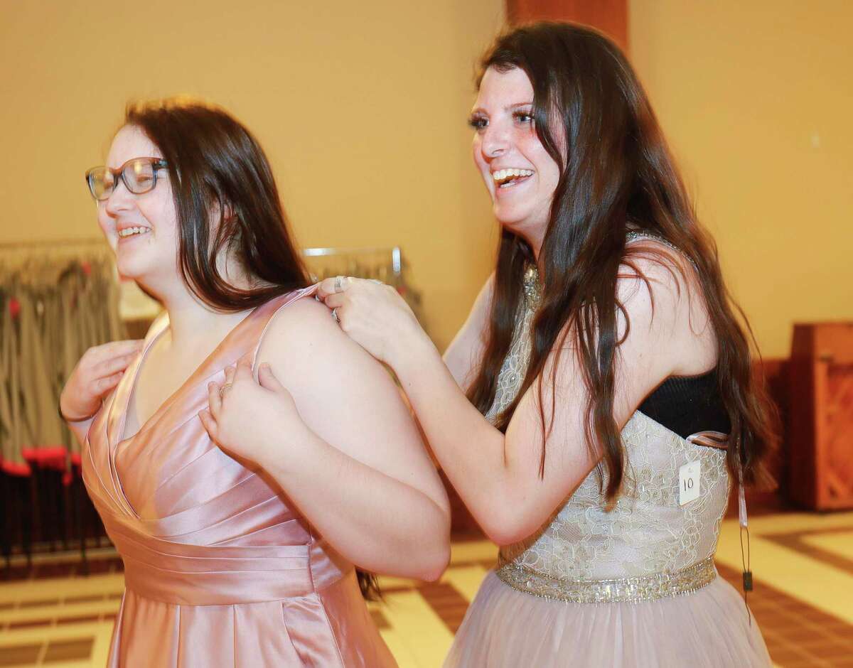 Kaylee Riley, left, laughs with her friend Kayden Varney as she helps Riley decide on a prom dress during Priceless Gowns at First Baptist Church Conroe, Thursday, April 7, 2022, in Conroe. The annual ministry, which returned to full capacity after being canceled in 2020 and scaled back in 2021, allows high school and junior teens to shop for their prom gowns for free.