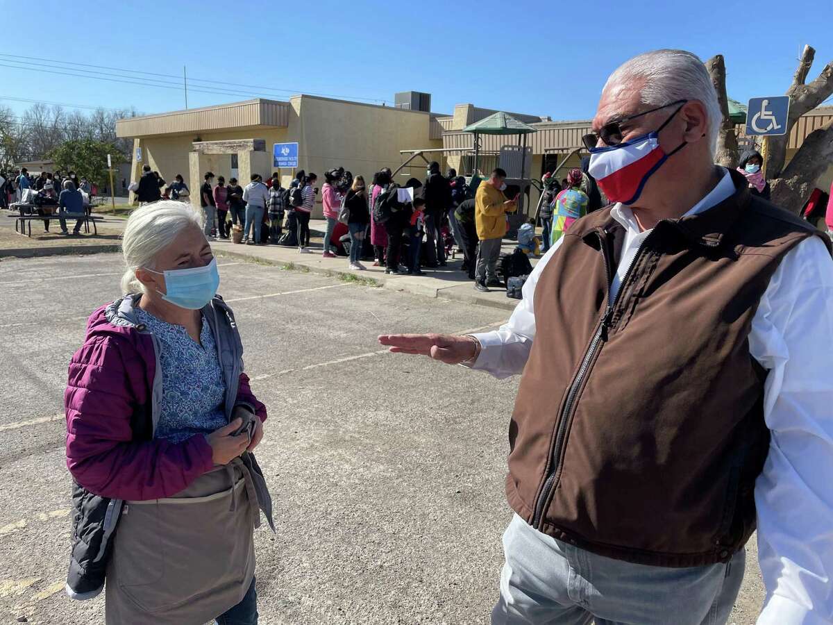 Tiffany Burrow, director of the Val Verde Border Humanitarian Coalition, left, speaks with Val Verde County Sheriff Joe Frank Martinez as asylum seekers await transportation in the background.