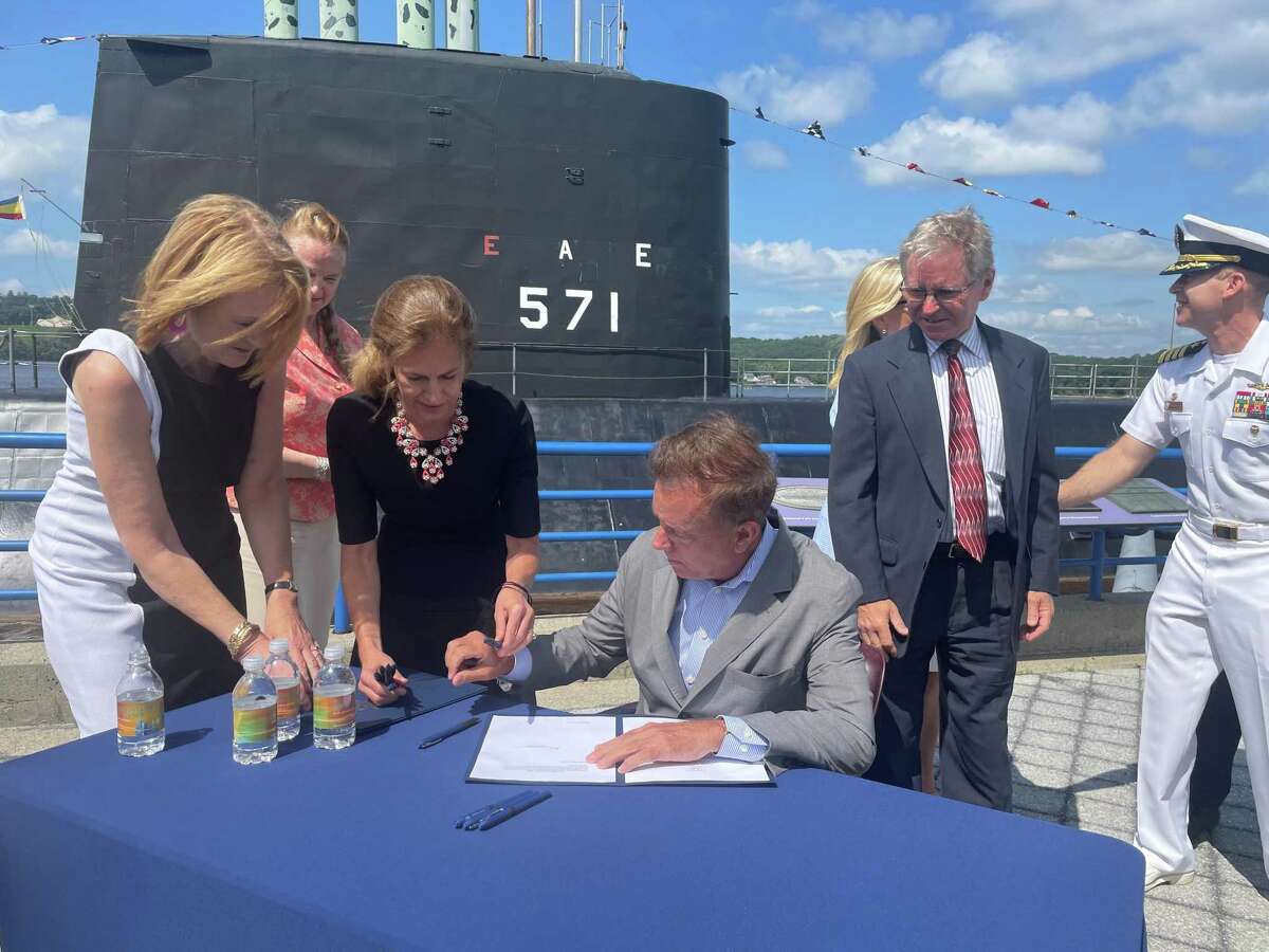 In a 2021 file photo, Gov. Ned Lamont signed a law in front of the USS Nautilus in Groton. On Friday, the governor, who is quarantining with COVID, signed a bill during a virtual meeting with state reporters.