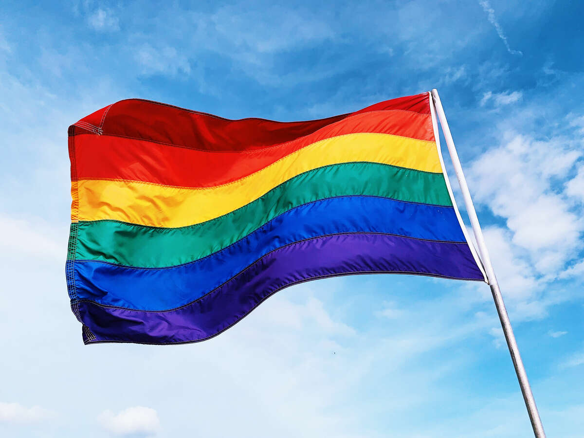 A rainbow flag waves in the wind.