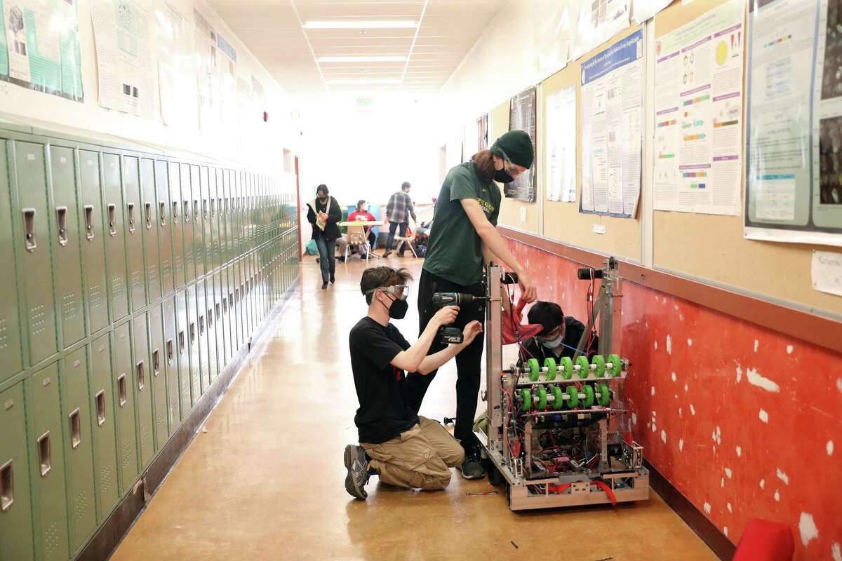 Cole Lewis, Lucas Rosenthal-Jones and Aiden Shiu prepare Lowell High’s competition robot “Sparrow” ahead of a regional contest.