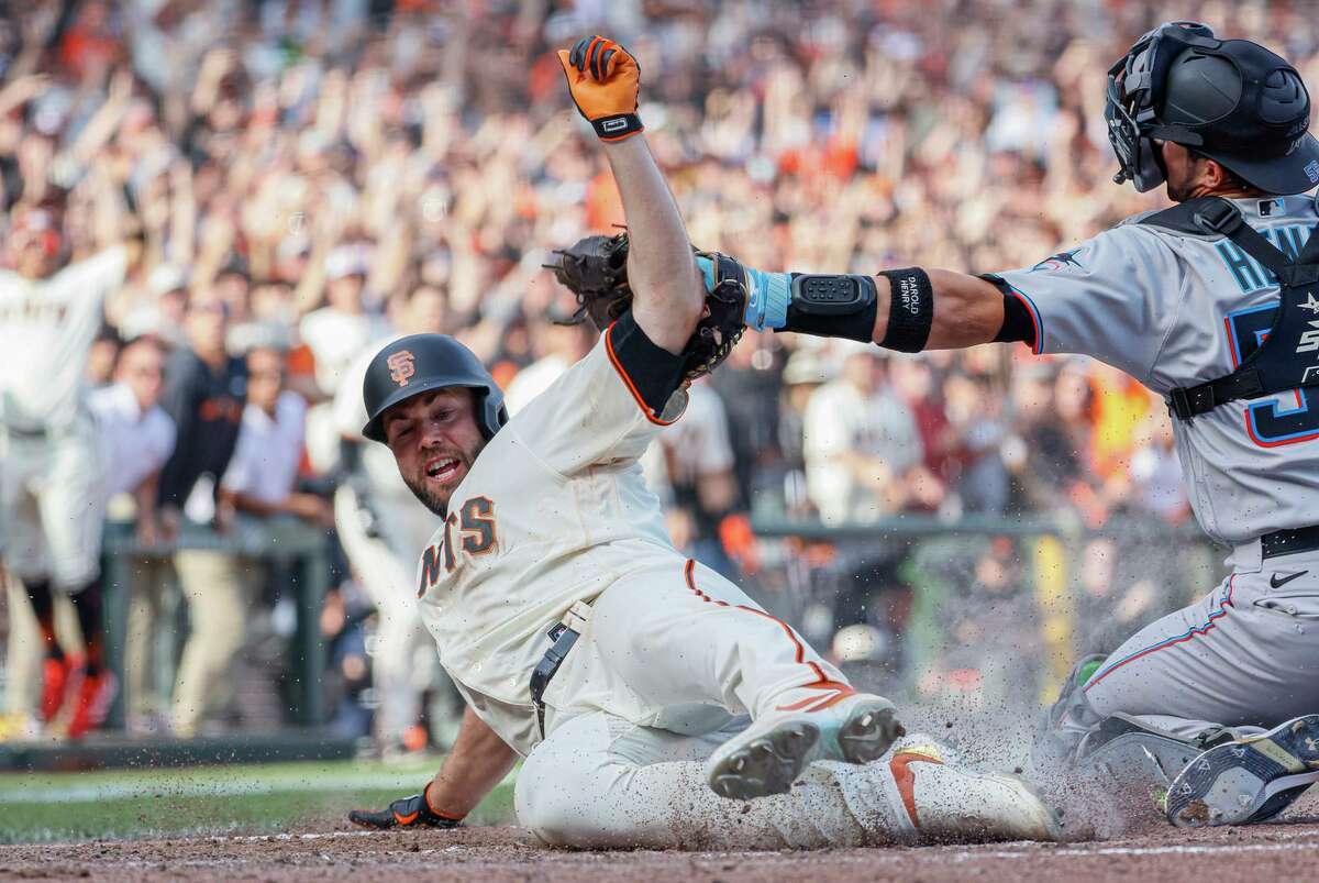 San Francisco Giants Darin Ruf (33) slides past Miami Marlins catcher Payton Henry (59) and scores to win the MLB game in the tenth inning against the Miami Marlins, Friday, April 8, 2022, in San Francisco, Calif. The Giants won 6-5.