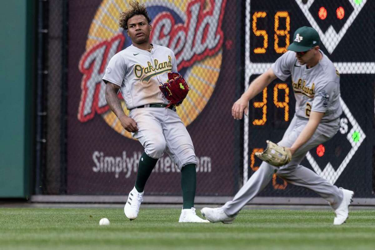 Oakland Athletics center fielder Cristian Pache, left, and right fielder Stephen Piscotty (25) chase an RBI single by Philadelphia Phillies' J.T. Realmuto during the third inning of a baseball game, Friday, April 8, 2022, in Philadelphia. (AP Photo/Laurence Kesterson)