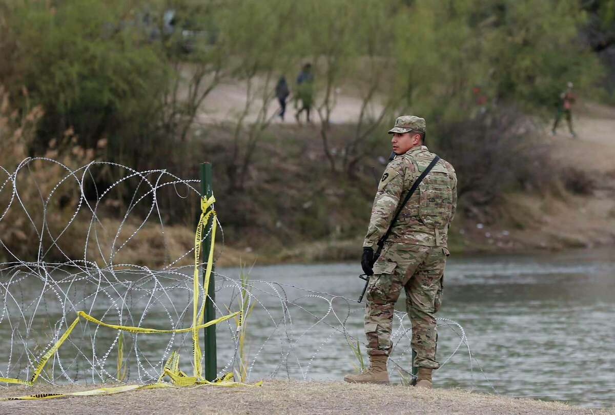 A Texas National Guardsman stands on the U.S. by a boat ramp on the Rio Grande near the international bridge in Eagle Pass on Jan. 12, 2022. The cost for Operation Lone Star, which has deployed 10,000 service members, has ballooned to more than $2 billion a year.