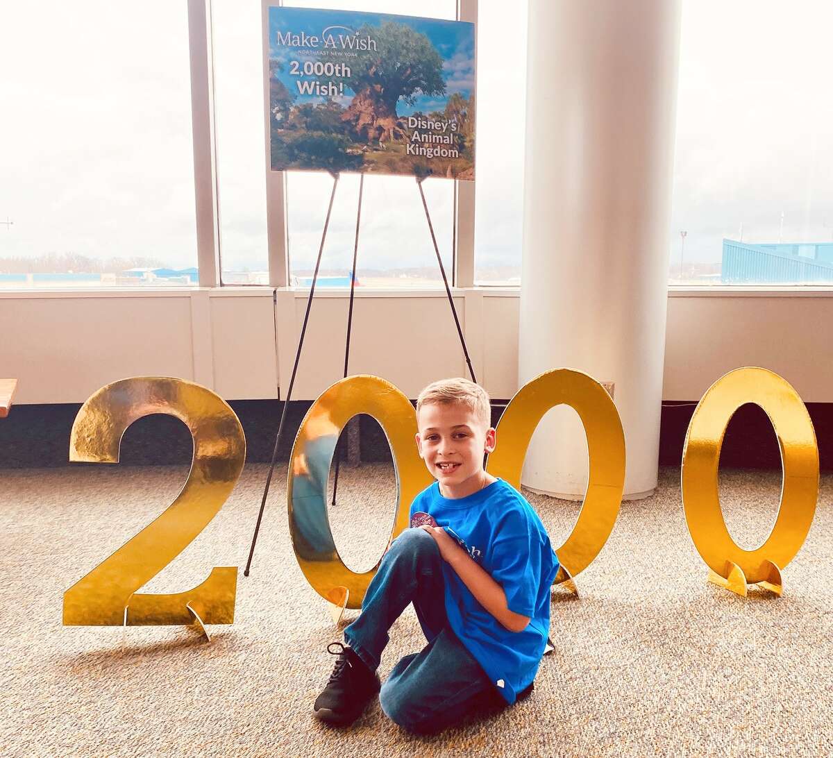 Anthony DiScipio, 7, poses next to a sign celebrating Make-A-Wish Northeast New York's 2,000th wish: his trip to Disney while fighting leukemia.