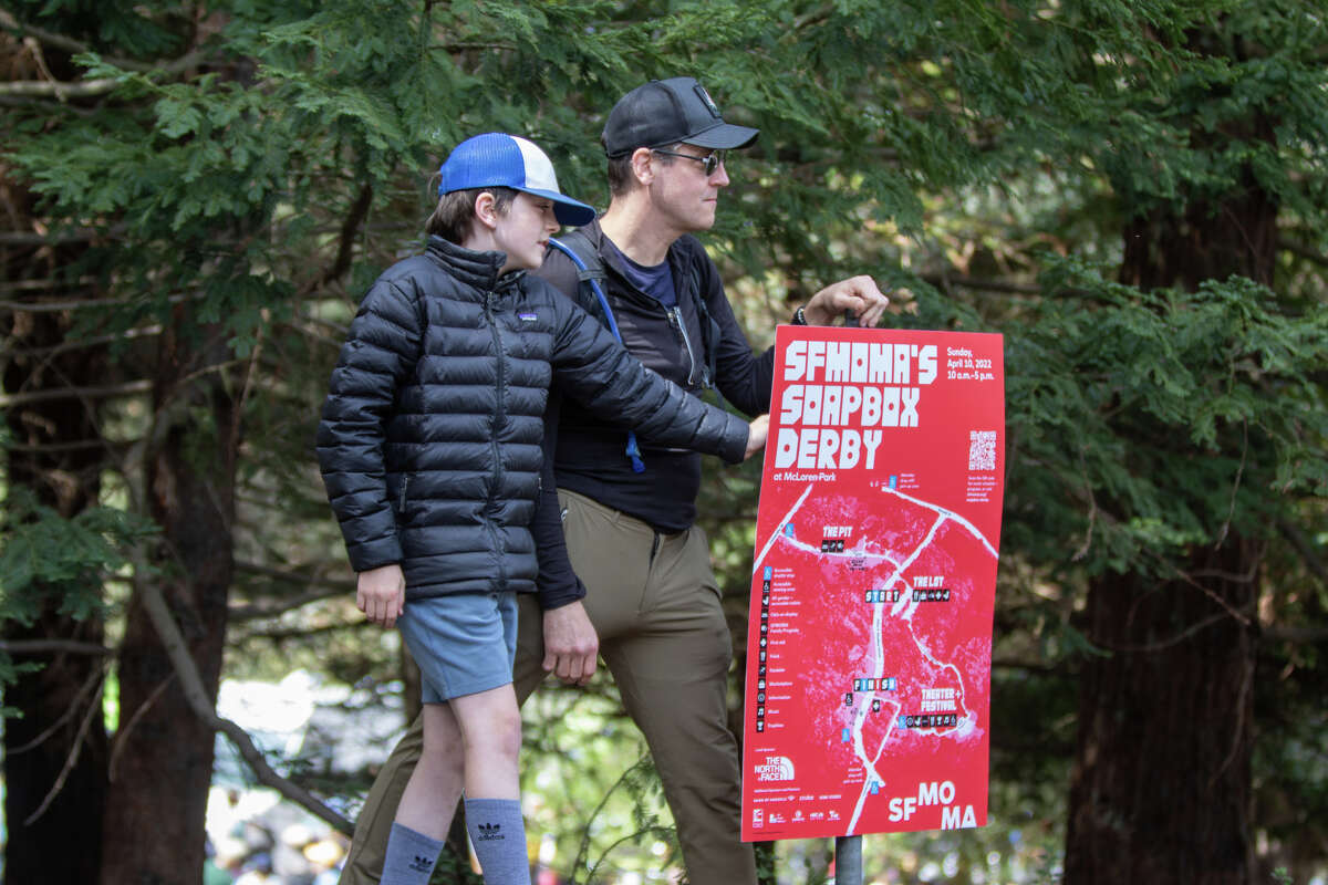 Deux spectateurs ont un bon point de vue sur les coureurs au SFMOMA Soapbox Derby à McLaren Park à San Francisco le 24 avril. 10, 2022.