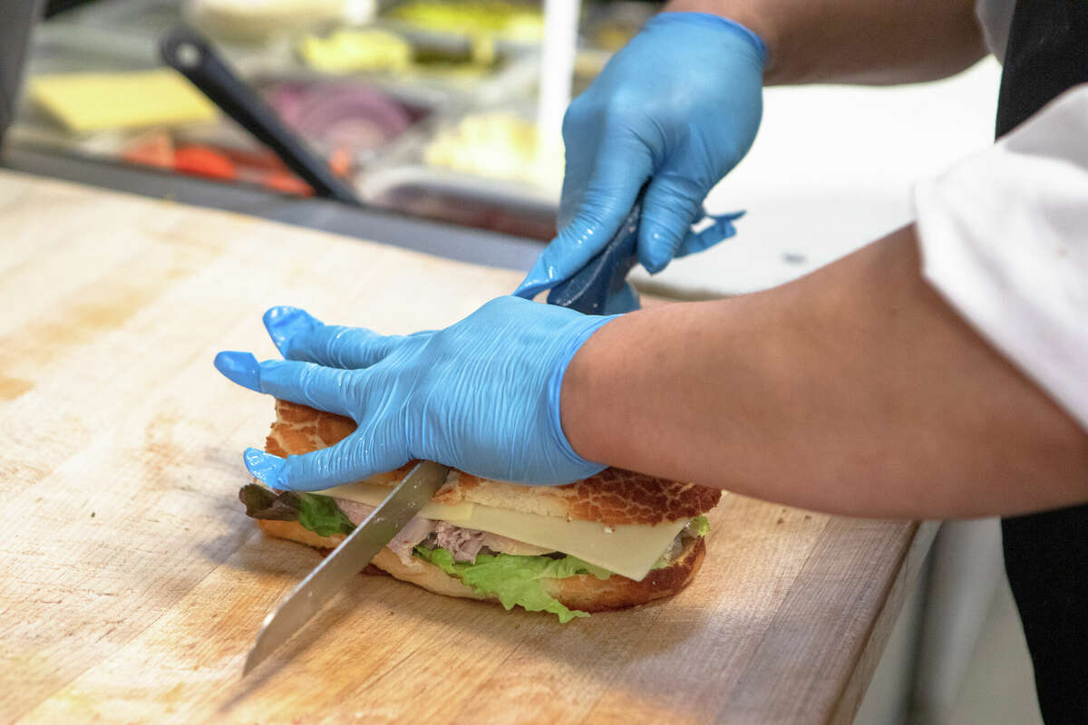 An employee cuts in half a hot roasted turkey sandwich at Arguello Market in San Francisco, Calif. on Apr. 10, 2022. The market is the self-described home of the 'World Famous Turkey Sandwich.'