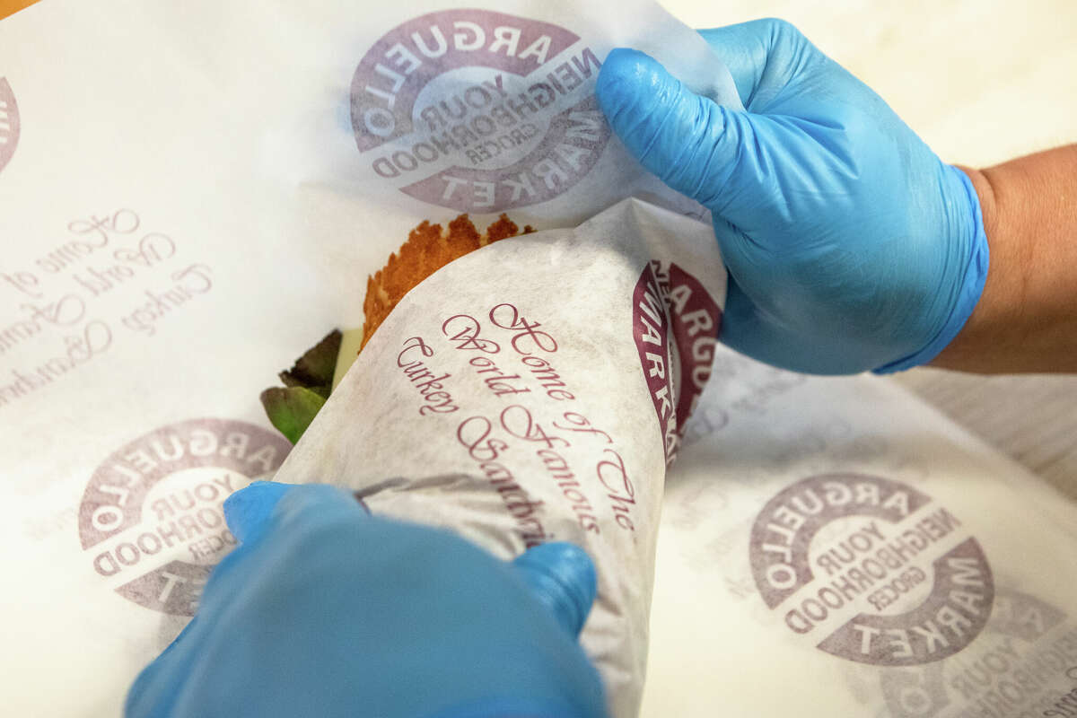 An employee wraps a hot roasted turkey sandwich at Arguello Market.