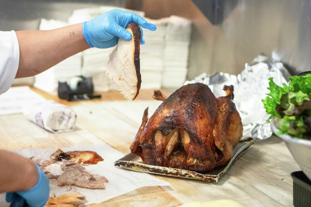 An employee slices a turkey to make a hot roasted turkey sandwich at Arguello Market in San Francisco, Calif. on Apr. 10, 2022. The market is the self-described home of the 'World Famous Turkey Sandwich.'