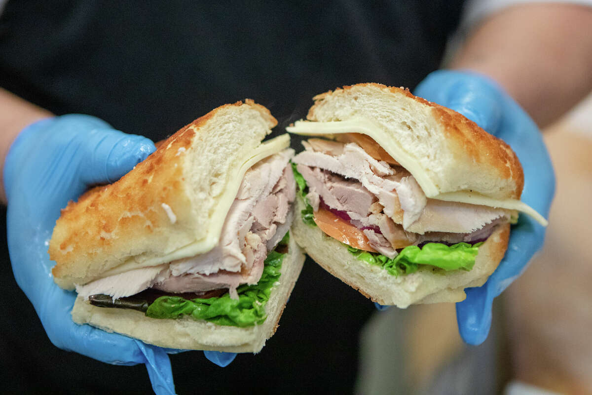 An employee holds a a hot roasted turkey sandwich at Arguello Market in San Francisco, Calif. on Apr. 10, 2022. The market is the self-described home of the 'World Famous Turkey Sandwich.'