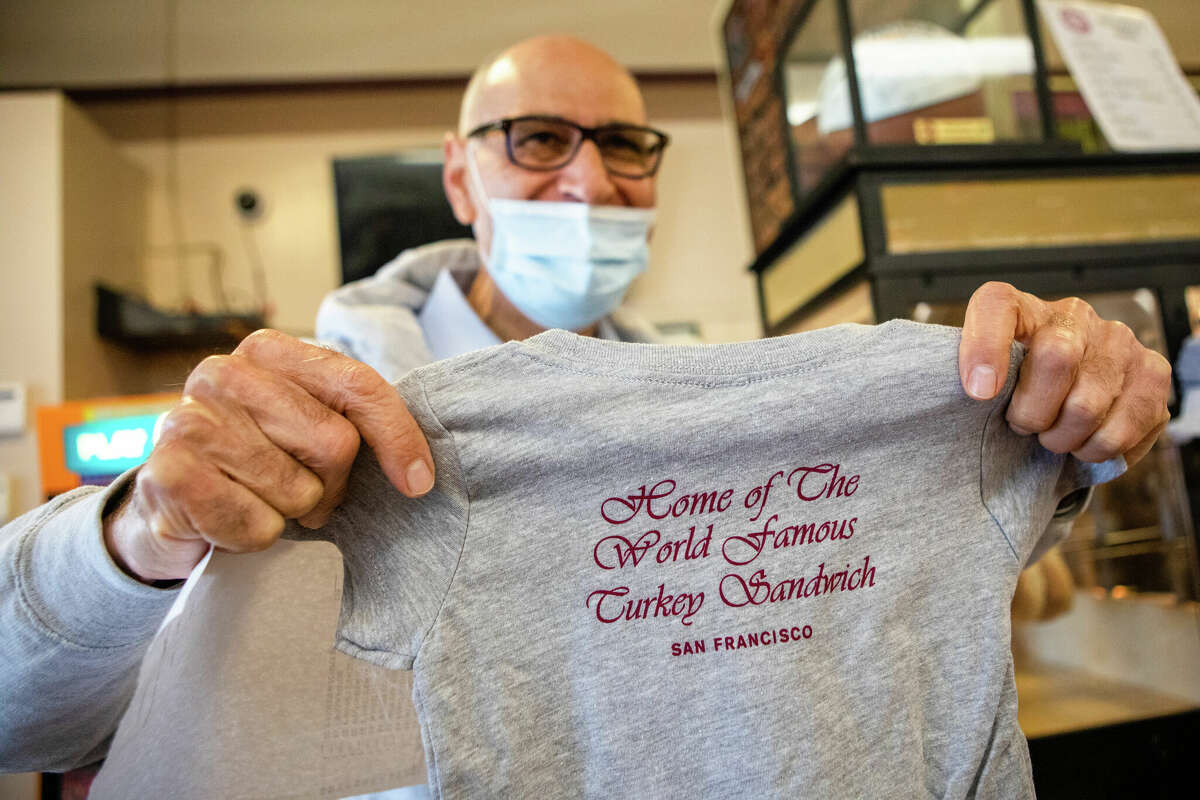 Owner Sal Qaqundah holds up one of his branded T-shirts at Arguello Market. The market is the self-described home of the 'World Famous Turkey Sandwich.'