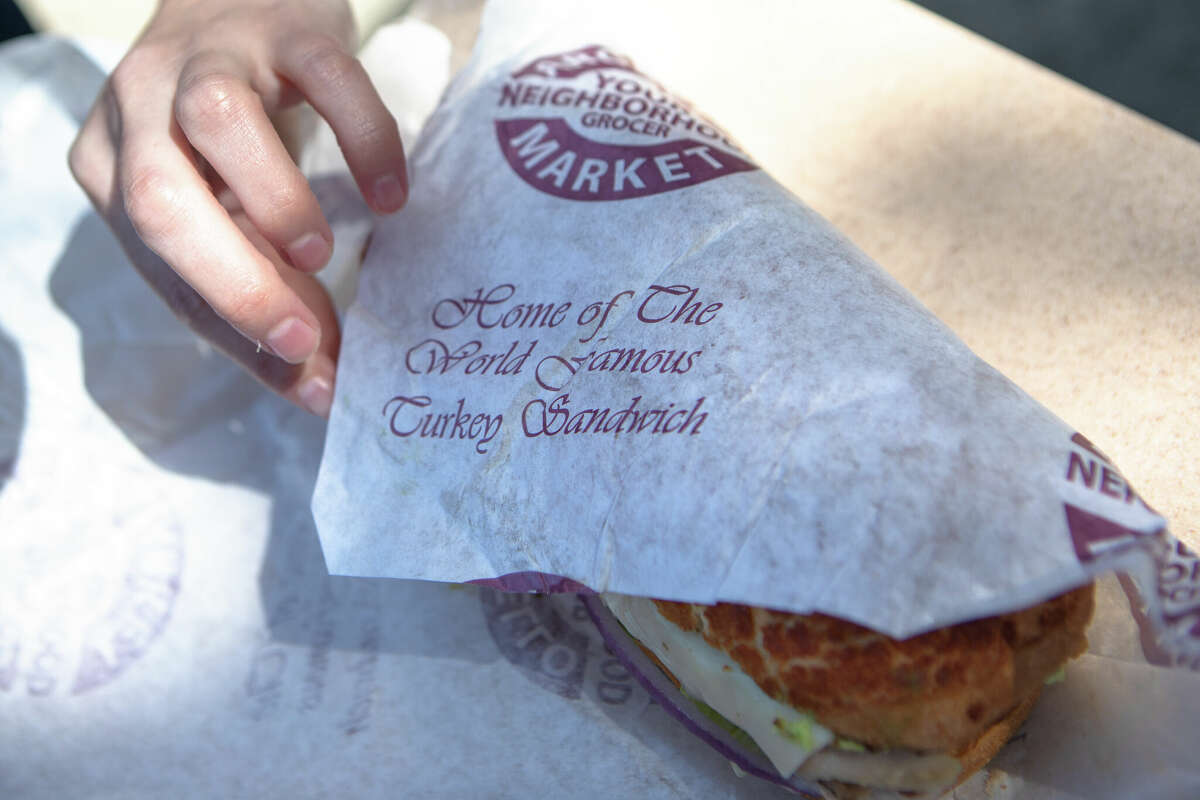 A customer opens up the wrapping paper for a hot roasted turkey sandwich at Arguello Market in San Francisco, Calif. on Apr. 10, 2022. The market is the self-described home of the 'World Famous Turkey Sandwich.'