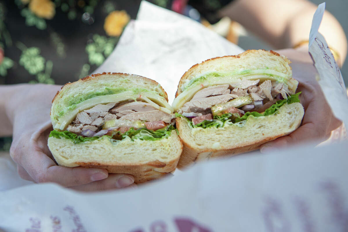 10 Nisan 2022'de San Francisco, California'daki Arguello Market'te bir müşteri sıcak kavrulmuş hindili sandviç tutuyor. 