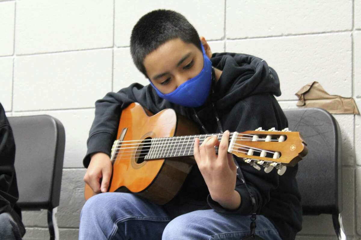 Sterling Middle School student Angel Martinez learns a new chord on the guitar during class.