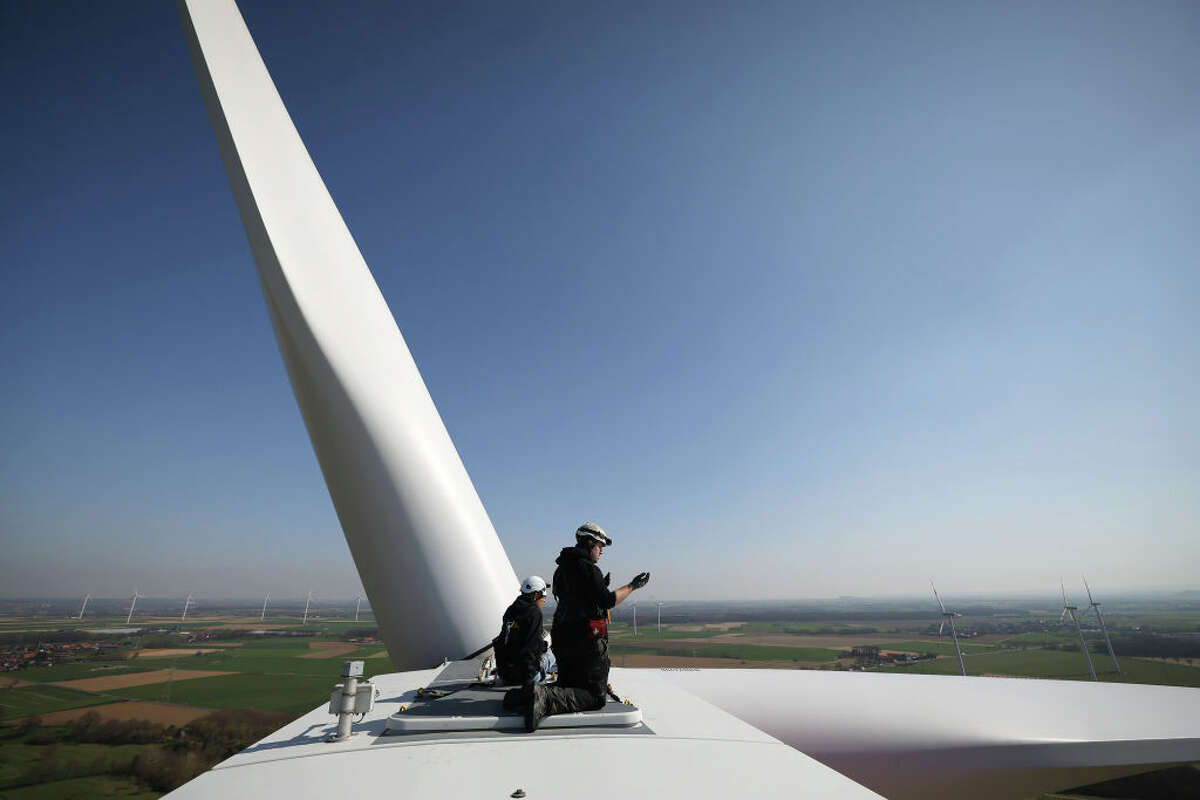 Technicians kneel on a wind turbine of a wind turbine of the Landesverband Erneuerbare Energien NRW (LEE NRW) at the Heinsberg-Straeten wind farm. (Photo by Oliver Berg/picture alliance via Getty Images)