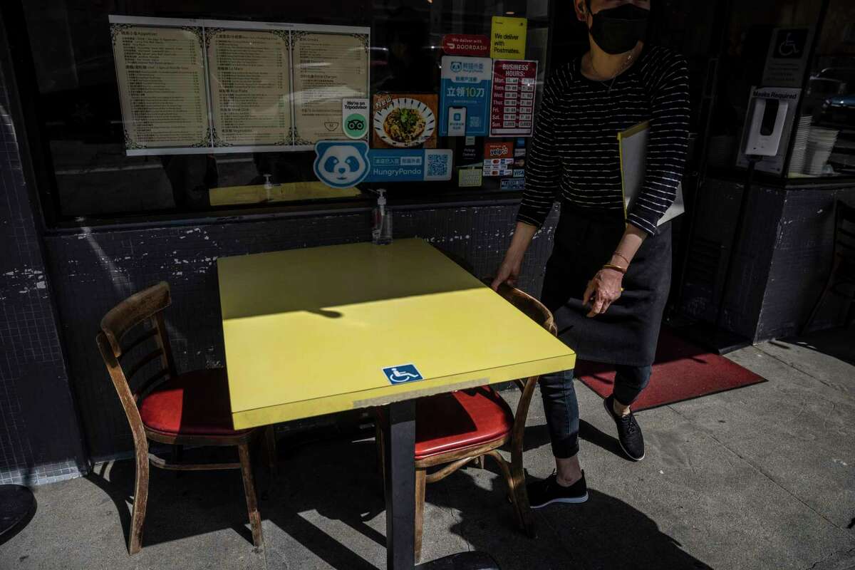 Amanda Yan, owner of Hon's Wun-Tun House, adjusts a chair at an Americans with Disabilities Act-compliant table outside the restaurant in the Chinatown neighborhood of San Francisco on April 7, 2022. Hon’s Wun-Tun House was sued by plaintiffs alleging a lack of wheelchair access to outdoor dining surfaces in April 2021, even though the restaurant served only takeout orders at that time, according to a lawsuit filed by the district attorneys of San Francisco and Los Angeles on Monday.