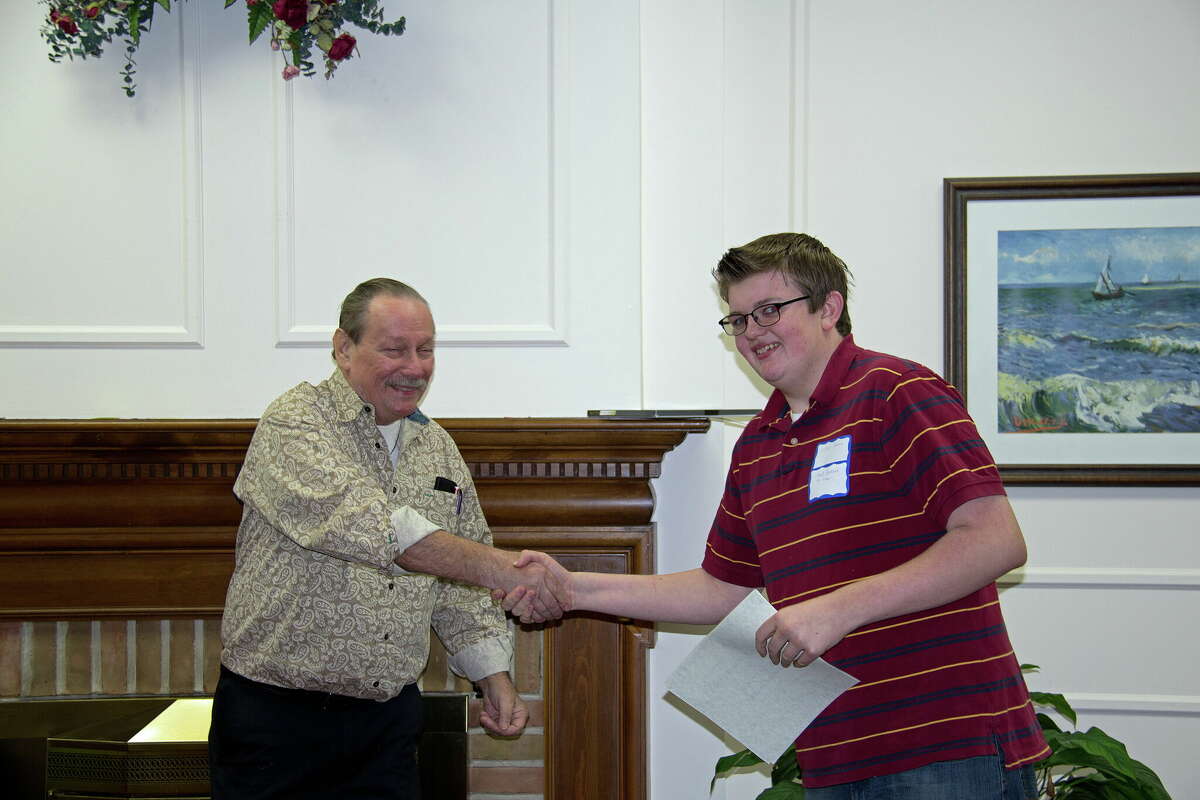 Dennis Collins, President of HAWG, presents a certificate and check to Will Johnson at a past awards ceremony for the writing contest, A Celebration of Young Writers. Johnson is now a judge for the contest.