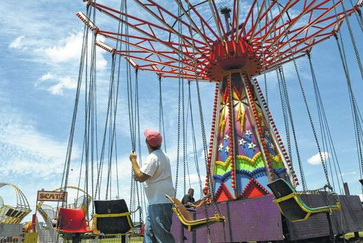 Adam Eustice of Conner Family Amusements of Beardstown straightens chains on a carnival ride at Pike County Fairgrounds in Pleasant Hill in 2018. Questions about ownership of three barns at the fairgrounds have put a wrinkle in a plan to remove them to create more parking space.