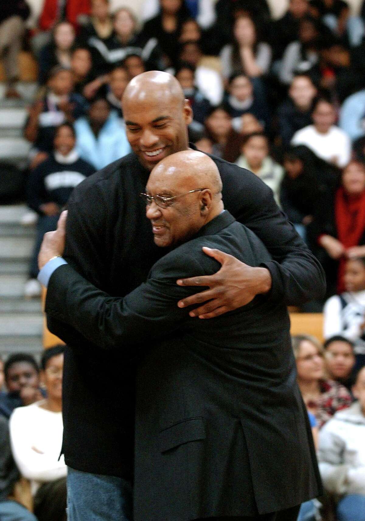 Sam Burrell, right, is hugged by his son Scott at the 2004 Walter Camp Stay-in-School Rally at East Haven High School.