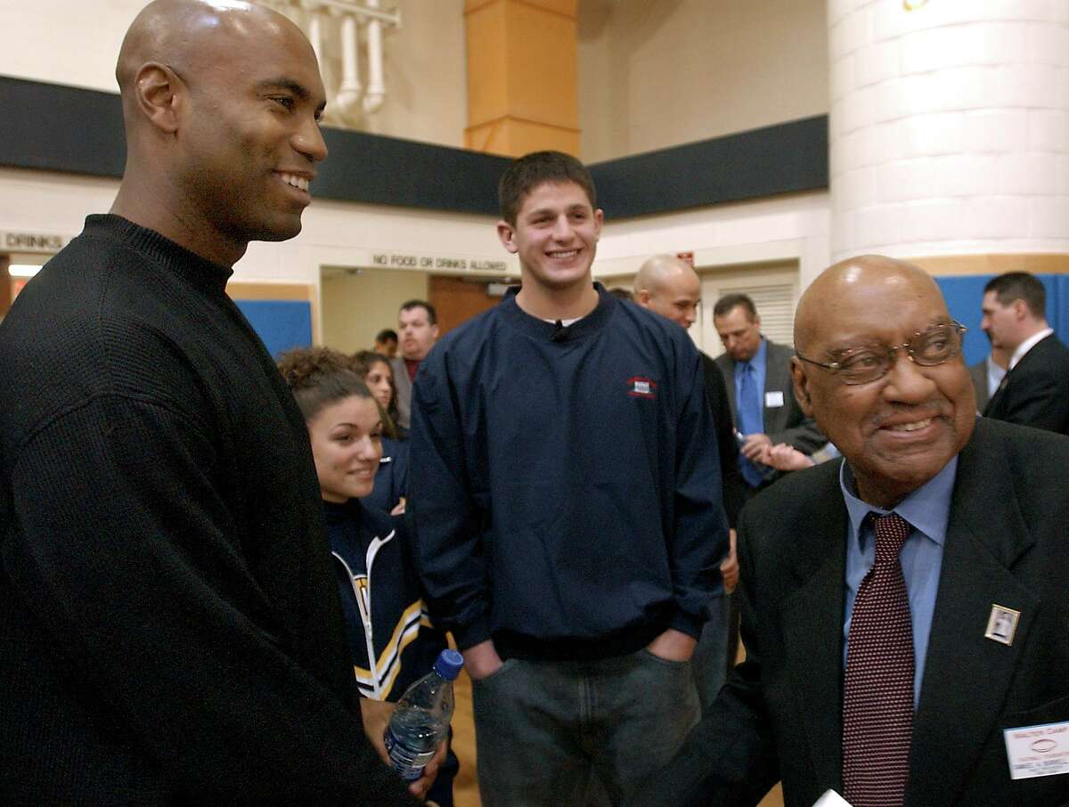 From left, Scott Burrell, UConn quarterback Dan Orlovsky, and Sam Burrell speak at the 2004 Walter Camp Stay-in-School Rally, which was organized by Sam, at East Haven High School.
