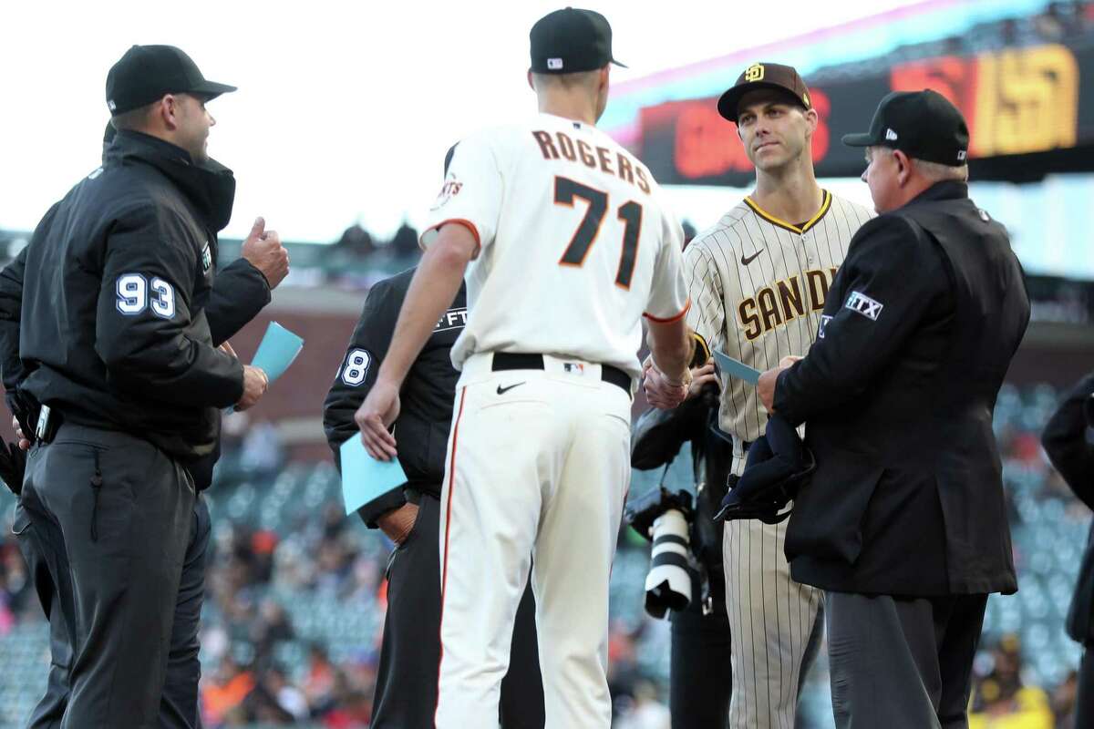 Brothers San Diego Padres’ Taylor Rogers and San Francisco Giants’ Tyler Rogers exchange line up cards before start of MLB game at Oracle Park in San Francisco, Calif, on Monday, April 11, 2022.