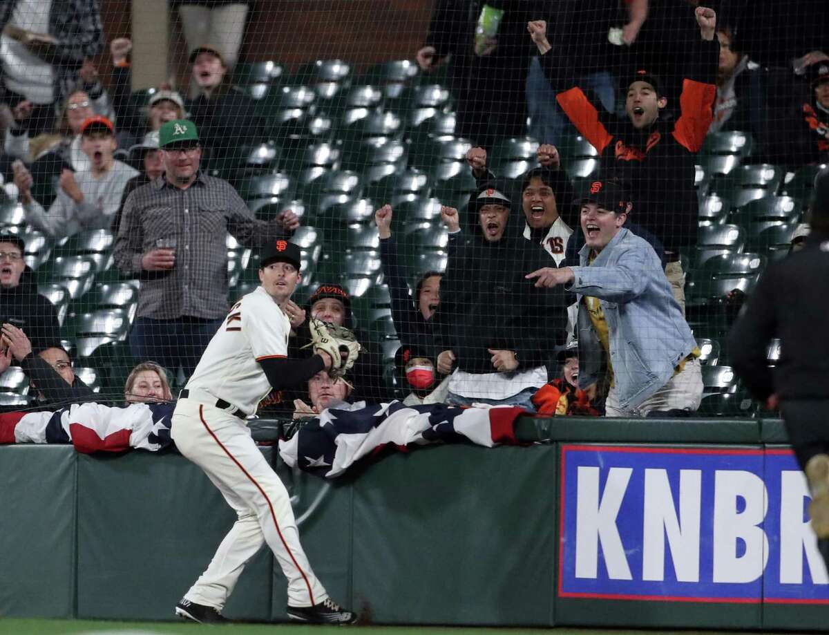 San Francisco Giants’ fans react to Mike Yastrzemski’s 2nd highlight catch of the game in foul territory, this 7th inning one off the bat of San Diego Padres’ Austin Nola during MLB game at Oracle Park in San Francisco, Calif, on Monday, April 11, 2022.