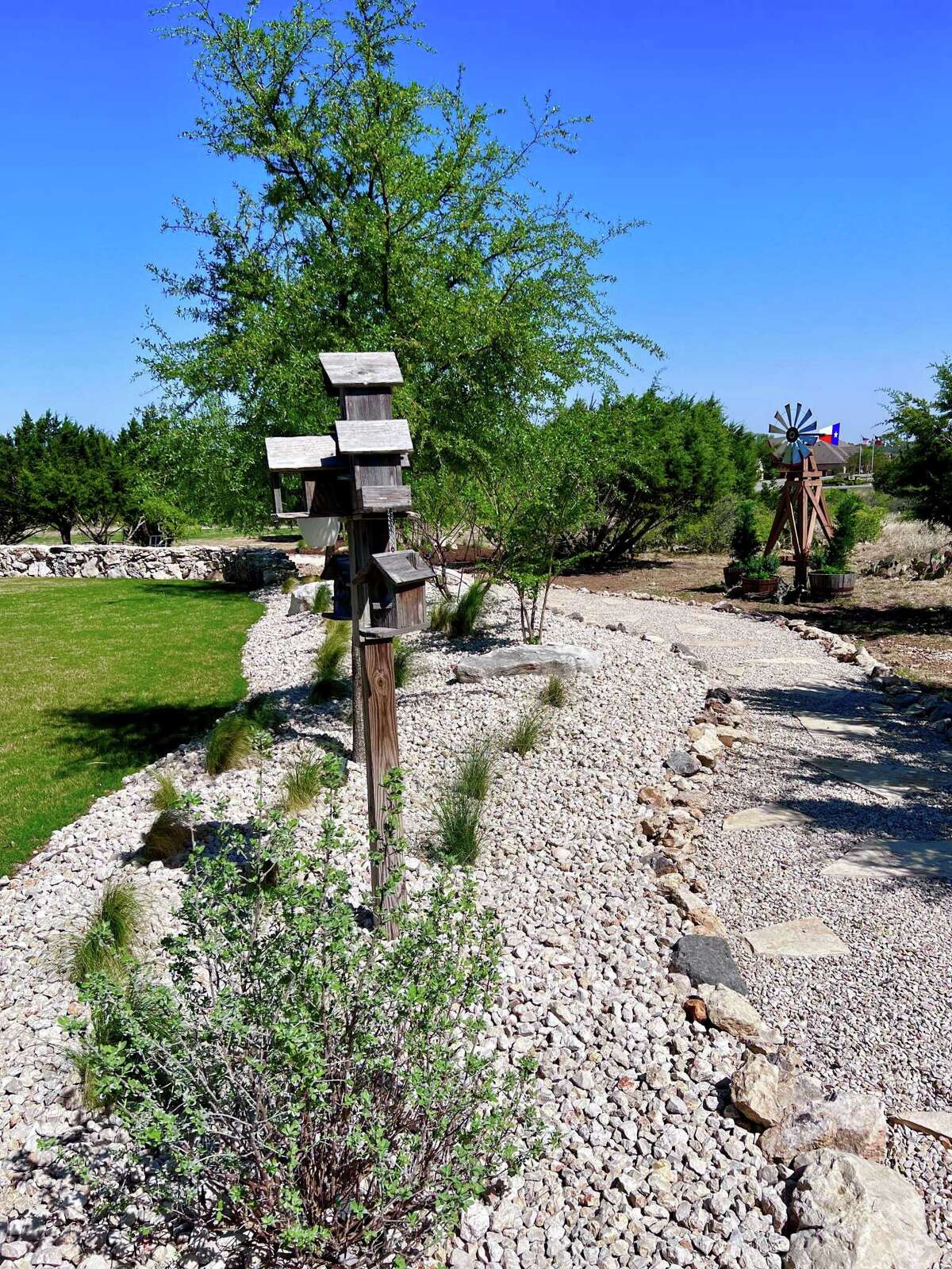Initially, the pathway that loops around the back of the yard was laid with mulch. But over time, that broke down and was washed away by rainstorms. So last year, the homeowners replaced it with limestone gravel bordered by decorative rock.
