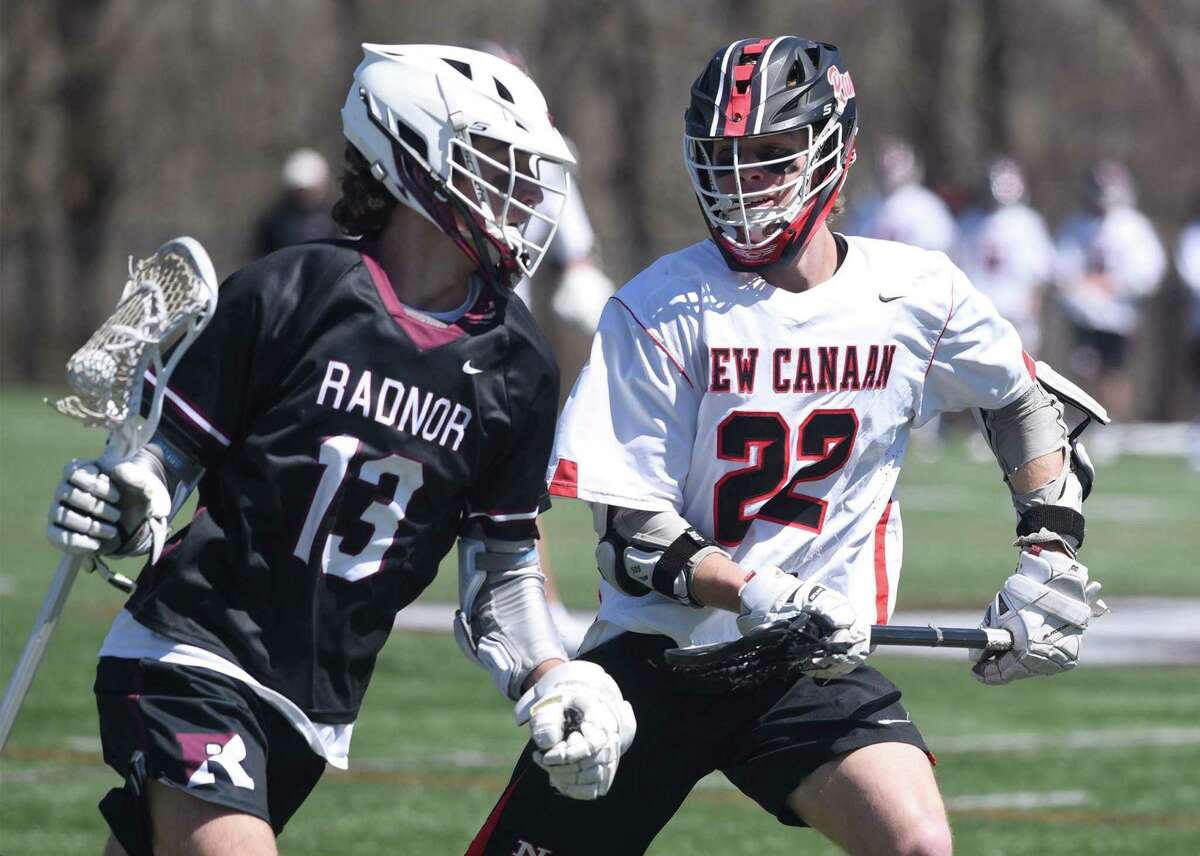 New Canaan's Walker Blair (22) defends against Radnor's Cooper Mueller (13) during a boys lacrosse game in New Canaan on Tuesday, April 12, 2022.