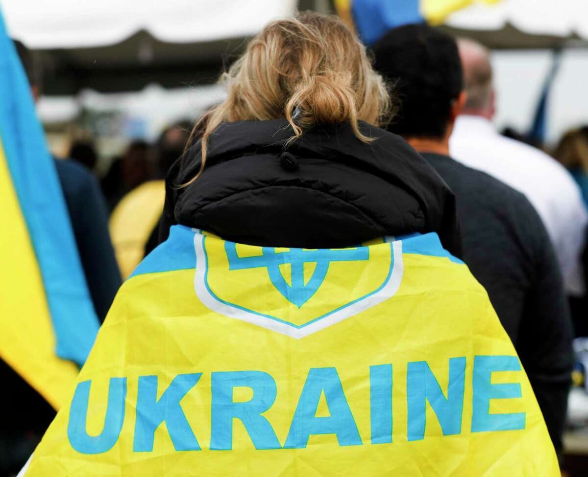 A woman wears a Ukraine flag over her shoulders as veterans and community members gathered at the Montgomery County Veterans Memorial Park to show support for the people of Ukraine, Friday, March 11, 2022, in Conroe.