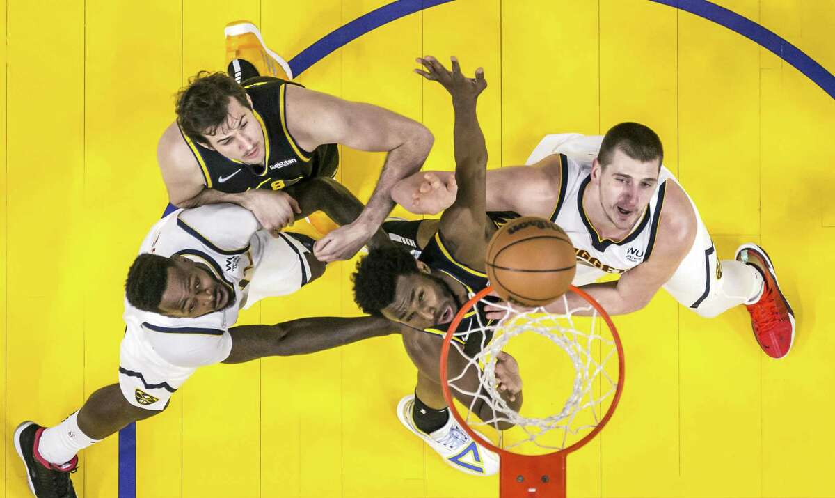 Andrew Wiggins (22) defends against a shot by Nikola Jokic (15) as the Golden State Warriors played the Denver Nuggets at Chase Center in San Francisco, Calif., on Wednesday, February 16, 2022. The Warriors were defeated 117-116 on a last second three pointer by Monte Morris (11)