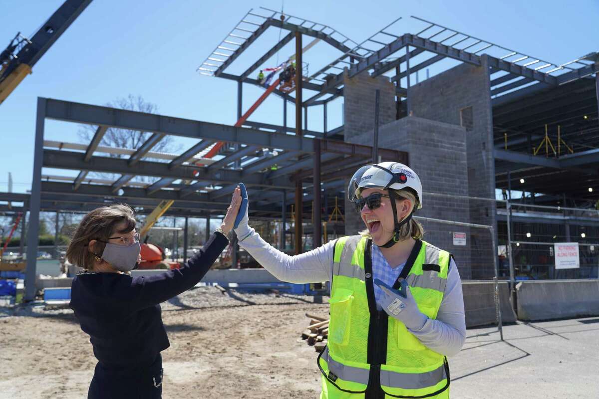 New Canaan Library Executive Director Lisa Oldham, left, and Turner Construction Project Manager Gillian Zinser gave high fives after steel workers placed the last beam of the new structure's frame on April 12, 2022.Lisa Oldham