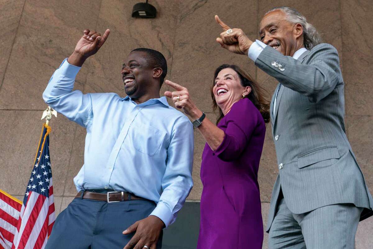 FILE — New York Gov. Kathy Hochul, center, state Sen. Brian Benjamin, right, and the Rev. Al Sharpton dance on stage during an event in the Harlem neighborhood of New York, Aug. 26, 2021, in New York. Benjamin resigned Tuesday, April 12, 2022, in the wake of his arrest in a federal corruption investigation. (AP Photo/Mary Altaffer, File)