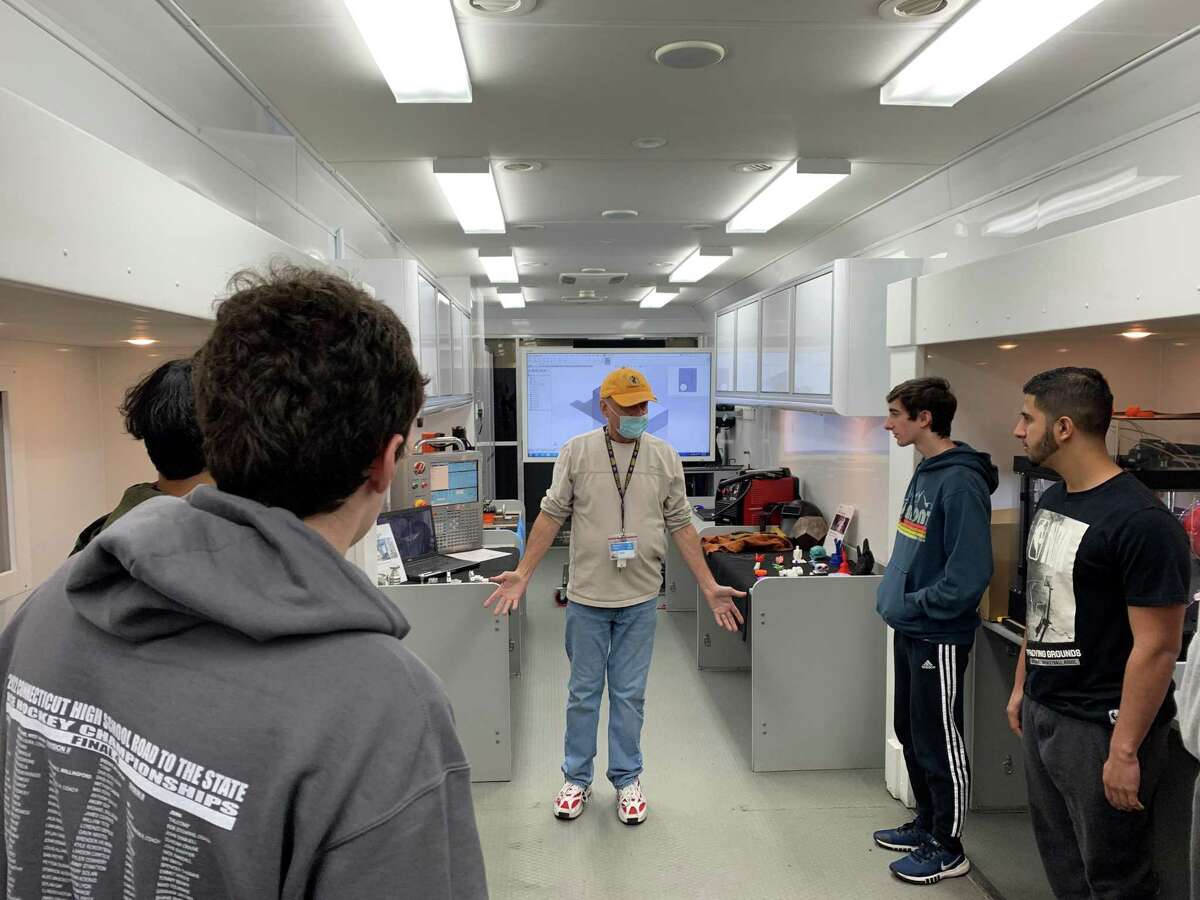 Goodwin University employee Thomas Curry talks to Conard High School students inside the university's mobile manufacturing lab.