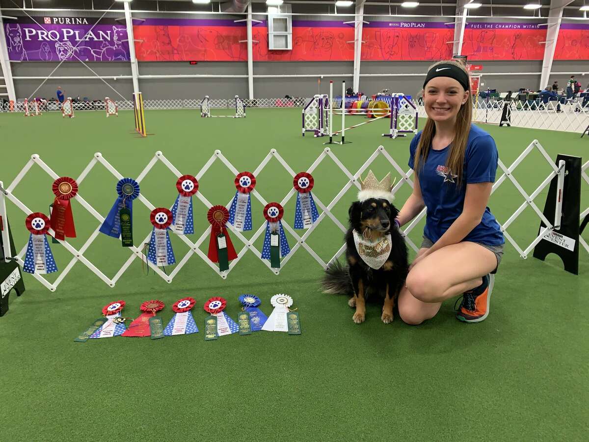 Allyssa Daube with her dog, Piper Grace, exhibit their placement ribbons from competition. The two will compete in agility contests this summer in Finland. 