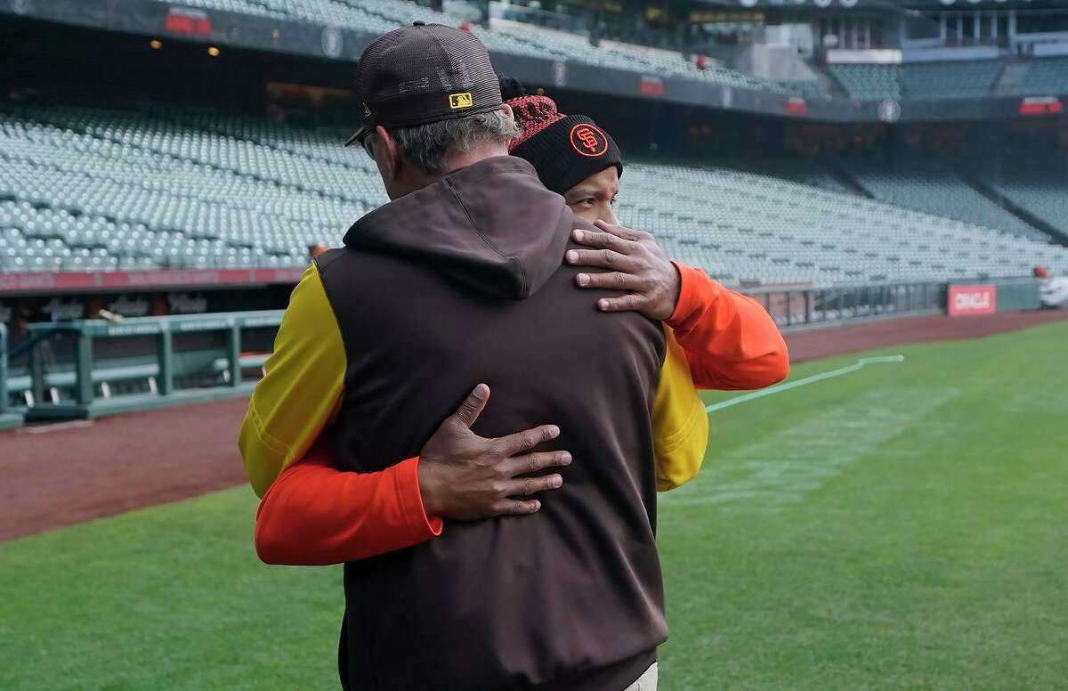 San Diego Padres third base coach Mike Shildt, back to camera, hugs San Francisco Giants first base coach Antoan Richardson after they spoke at a news conference before a baseball game in San Francisco, Wednesday, April 13, 2022. (AP Photo/Jeff Chiu)