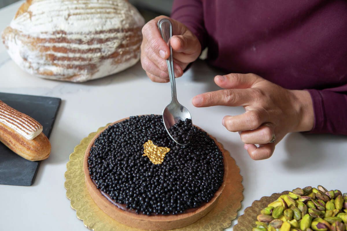 Monique Feybesse adds the finishing touches to a Chocolate 'Caviar" tart in her home kitchen in Vallejo, Calif. on April 8, 2022. The "caviar" are actually small pieces of chocolate. Monique and her husband Paul bake all the pastries and breads created by their company Tarts de FeyBesse themselves.