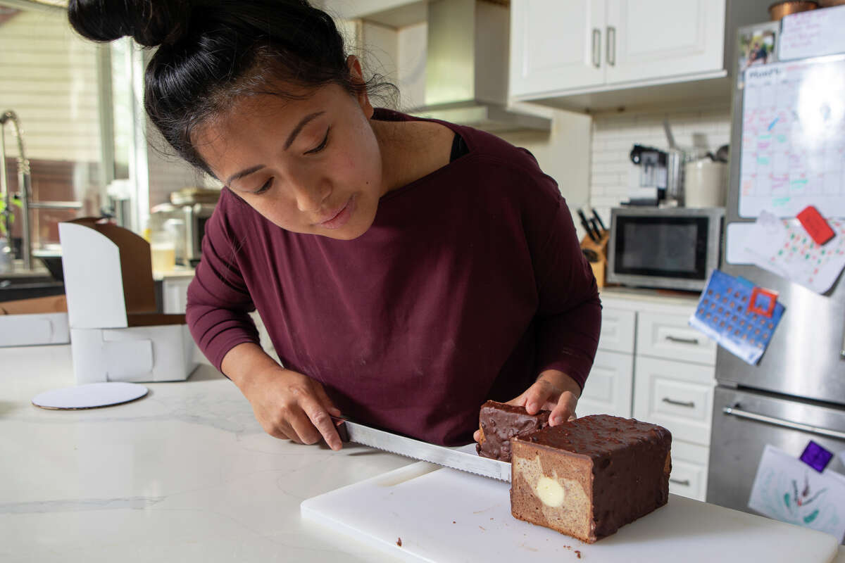 Monique Feybesse inspects a freshly made TDF Style Banana Bread in her home kitchen in Vallejo, Calif., on April 8. The bread consists of marbled banana loaf cake, roasted banana caramel and a chocolate crunch made with banana chips.