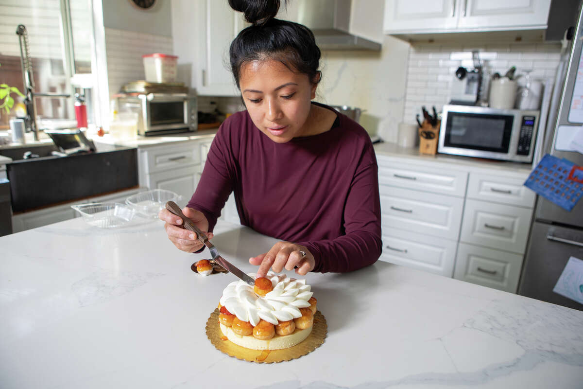 Monique Feybesse places a choux puff onto a St. Honore tart in her home kitchen in Vallejo, Calif., on April 8. She and her husband Paul bake all the pastries and breads created by their company Tarts de Feybesse themselves.