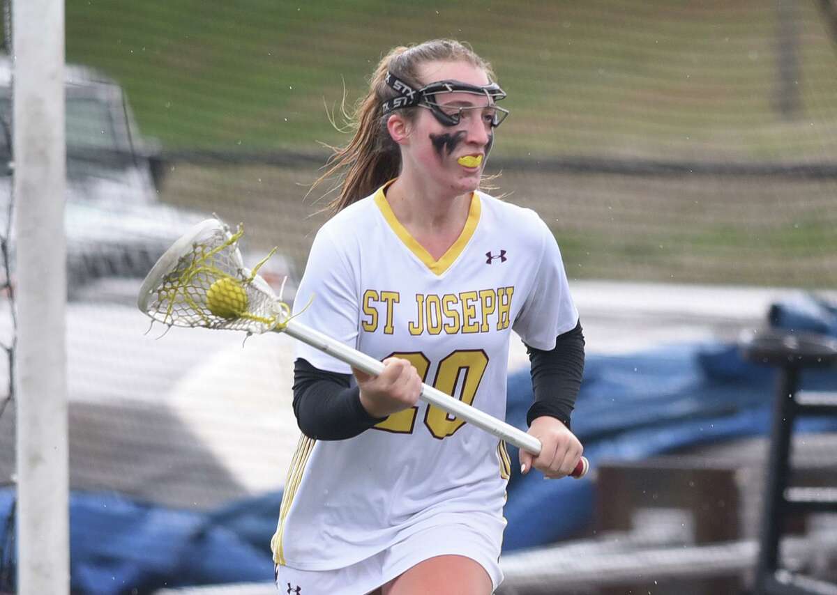 St. Joseph’s Meghan Hoynes (20) carries the ball during the Cadets’ girls lacrosse game against Newtown in Trumbull on Saturday, April 9, 2022.