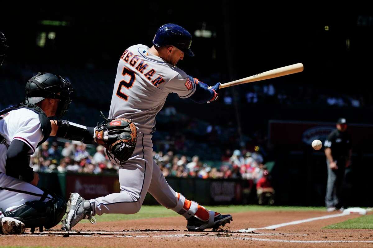Houston Astros' Alex Bregman (2) hits an infield grounder as Arizona Diamondbacks catcher Carson Kelly, left, looks on during the first inning of a baseball game Wednesday, April 13, 2022, in Phoenix. (AP Photo/Ross D. Franklin)