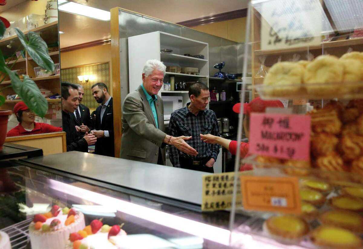 Former President Bill Clinton shakes hands with people inside of Washington Bakery & Restaurant during a surprise visit in Chinatown in 2016.